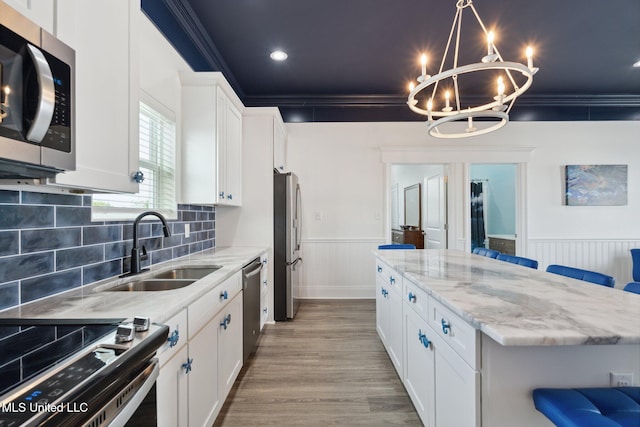 kitchen featuring crown molding, stainless steel appliances, white cabinetry, sink, and a breakfast bar