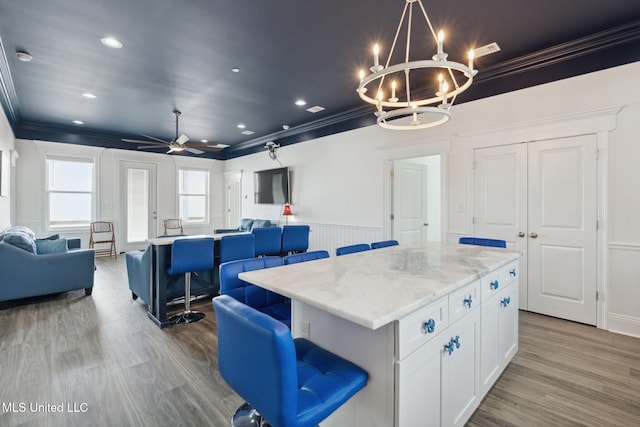 kitchen featuring white cabinetry, a kitchen bar, light hardwood / wood-style flooring, and a kitchen island