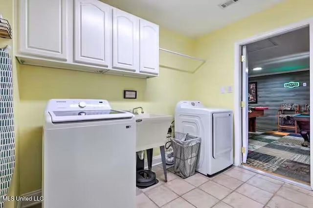 laundry room with light tile patterned flooring, cabinets, and washer and dryer