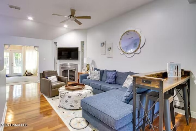 living room featuring hardwood / wood-style flooring, ceiling fan, vaulted ceiling, and french doors