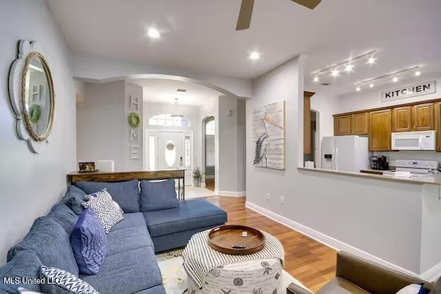 living room featuring rail lighting, ceiling fan, and light hardwood / wood-style flooring