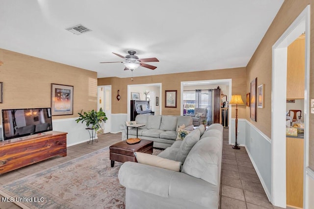 living room featuring a ceiling fan, visible vents, baseboards, and light tile patterned floors