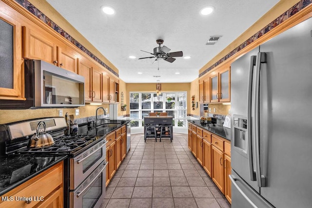 kitchen featuring glass insert cabinets, stainless steel appliances, a sink, and tile patterned floors