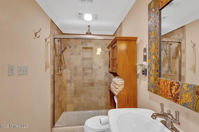 bathroom featuring a stall shower, visible vents, toilet, crown molding, and a sink