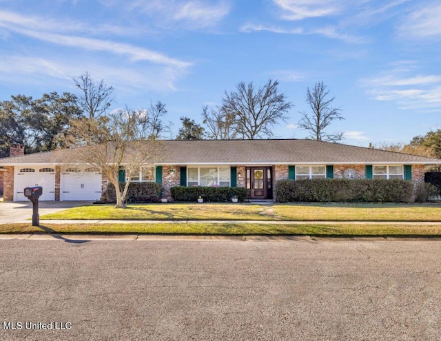 ranch-style house featuring a front yard, concrete driveway, and an attached garage