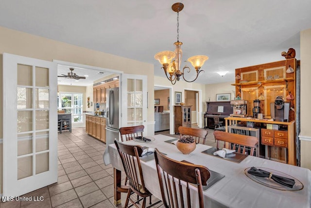 dining space with light tile patterned floors and ceiling fan with notable chandelier