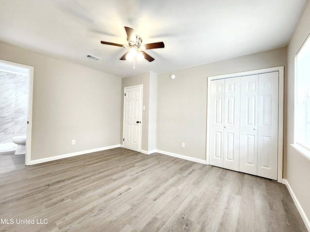 unfurnished bedroom featuring a closet, wood finished floors, visible vents, and baseboards