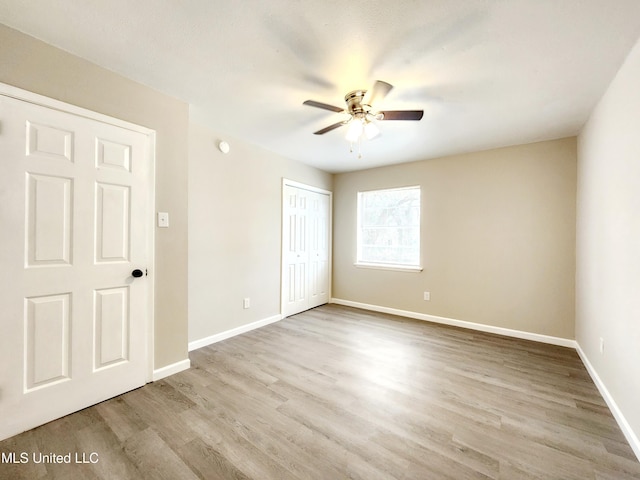 unfurnished bedroom featuring ceiling fan, a closet, wood finished floors, and baseboards