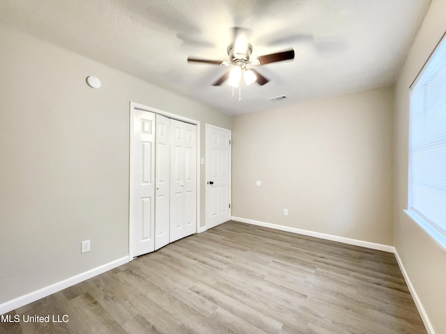 unfurnished bedroom featuring a closet, visible vents, baseboards, and wood finished floors