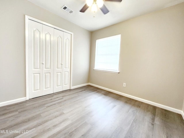 unfurnished bedroom featuring a closet, visible vents, a ceiling fan, wood finished floors, and baseboards