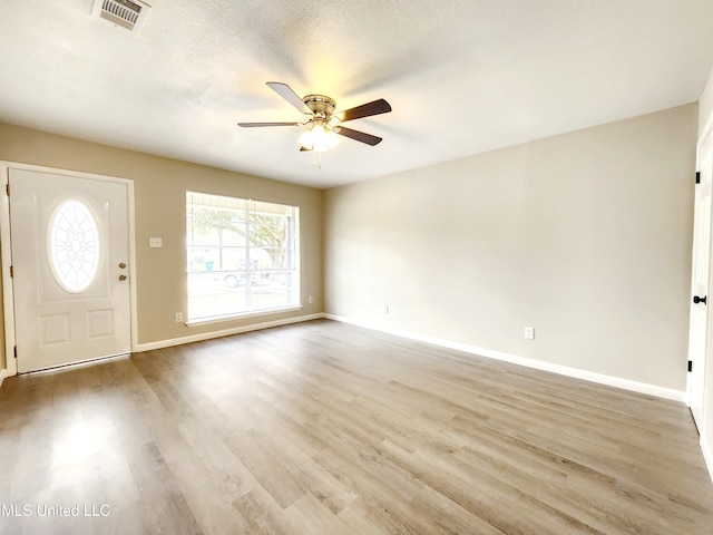 foyer entrance with visible vents, a ceiling fan, a textured ceiling, wood finished floors, and baseboards