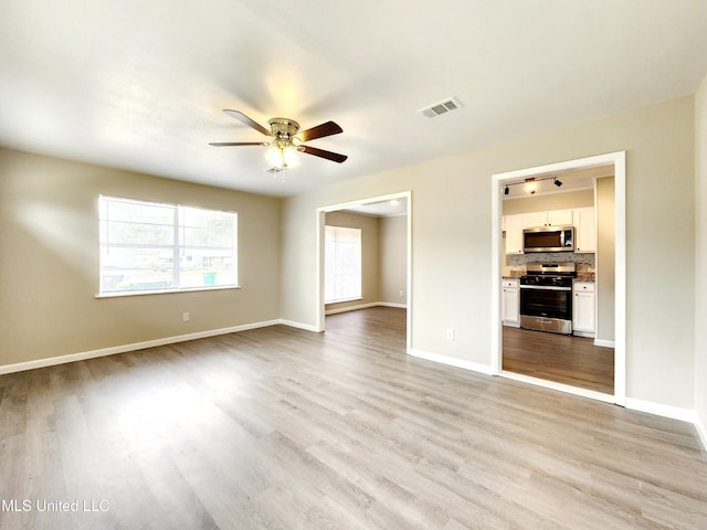 unfurnished room featuring light wood-type flooring, visible vents, ceiling fan, and baseboards