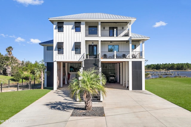 beach home featuring a carport, board and batten siding, covered porch, concrete driveway, and a balcony