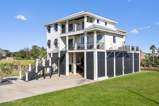 rear view of house with board and batten siding, stairs, a balcony, a yard, and a patio