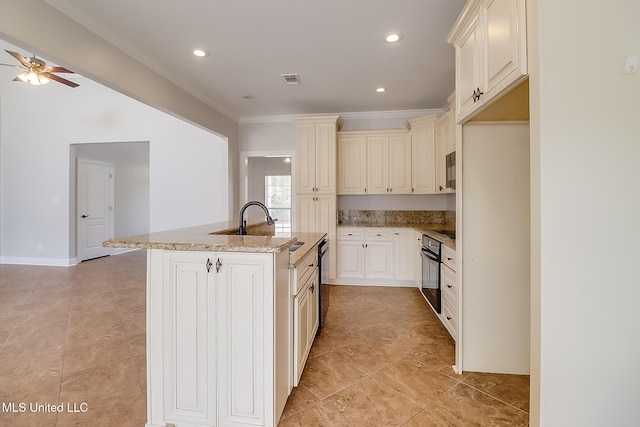 kitchen with crown molding, ceiling fan, light stone counters, black appliances, and a center island with sink