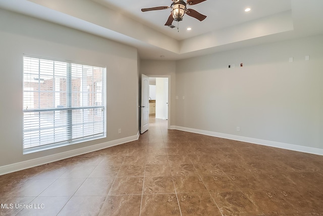 spare room with a tray ceiling and ceiling fan