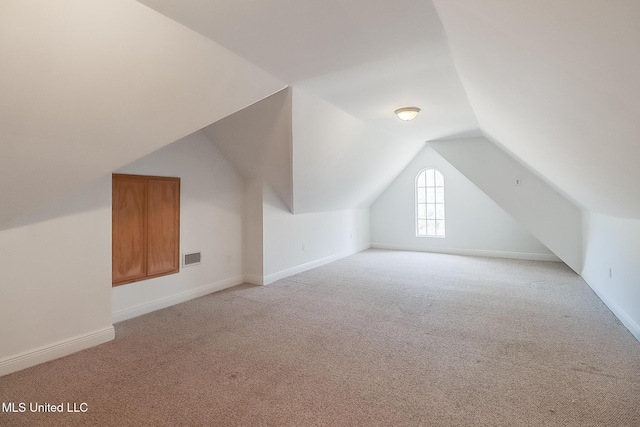 additional living space featuring lofted ceiling and light carpet