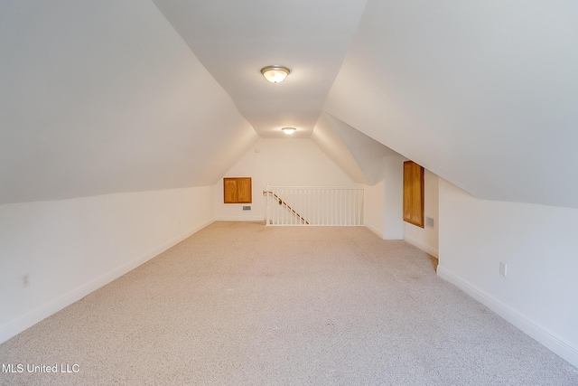 bonus room with vaulted ceiling and light carpet