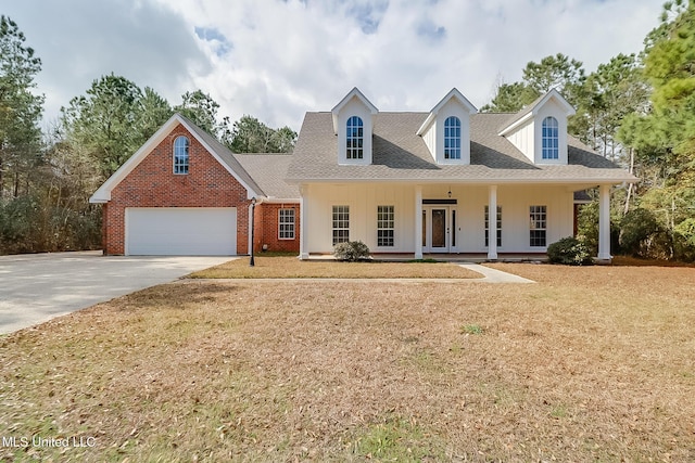 new england style home with a garage, a front yard, and covered porch