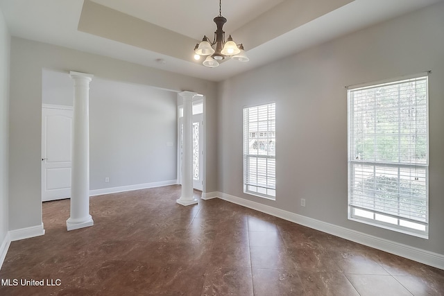 unfurnished room with a notable chandelier, decorative columns, a raised ceiling, and a healthy amount of sunlight