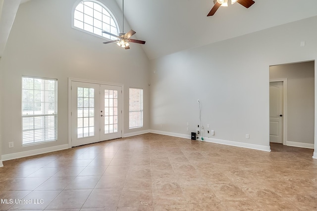 unfurnished living room featuring high vaulted ceiling, light tile patterned floors, ceiling fan, and french doors