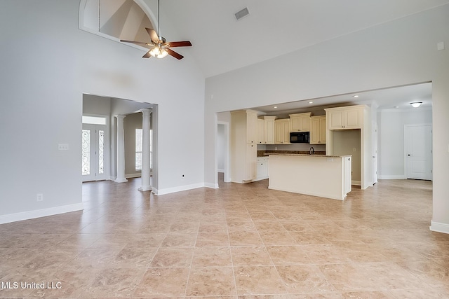 unfurnished living room featuring ceiling fan, light tile patterned floors, a high ceiling, and ornate columns