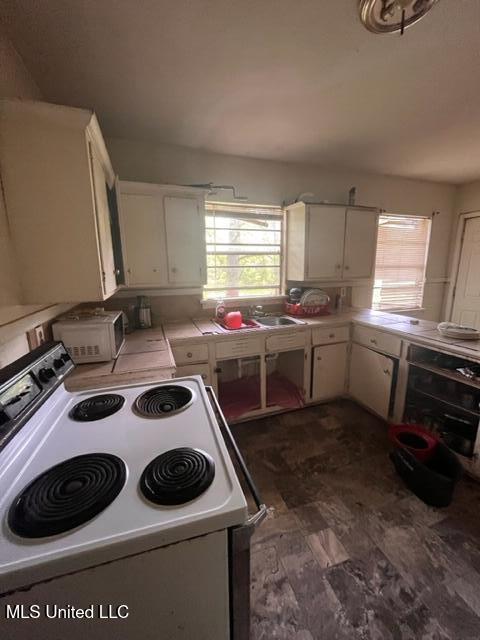 kitchen with white cabinets, sink, and white range with electric cooktop