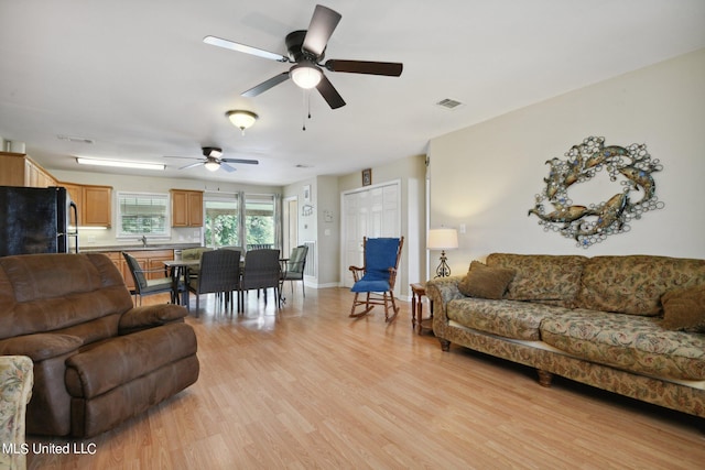 living room with sink, light hardwood / wood-style flooring, and ceiling fan