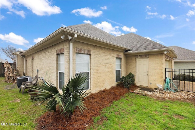 rear view of property with a yard and central air condition unit