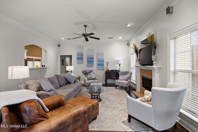 living room featuring ceiling fan, ornamental molding, and a fireplace