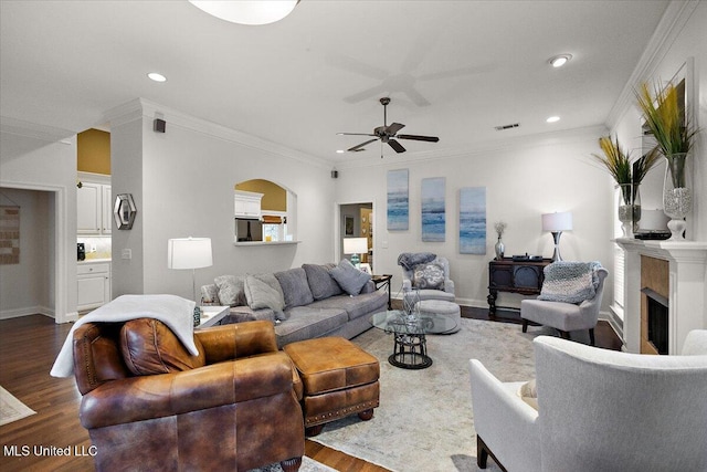 living room featuring dark hardwood / wood-style flooring, ornamental molding, and ceiling fan