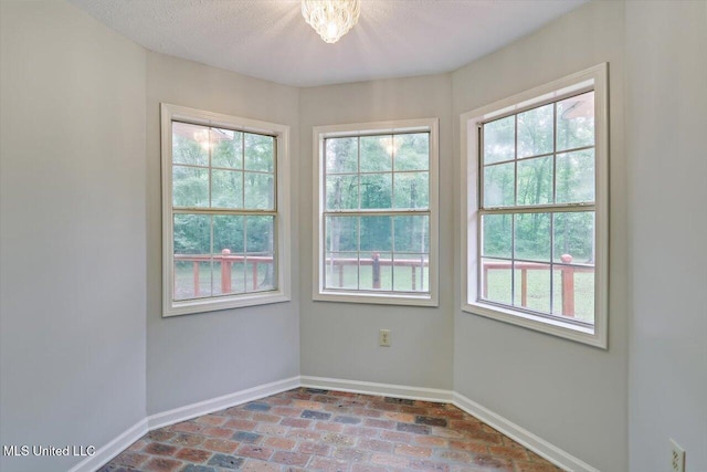 empty room featuring plenty of natural light, baseboards, and brick floor