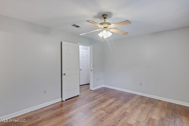 spare room featuring visible vents, baseboards, ceiling fan, and wood finished floors