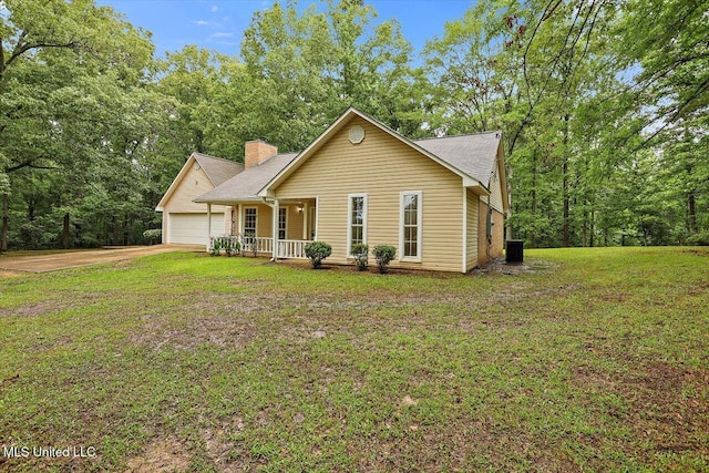view of front of house featuring covered porch, an attached garage, a chimney, and a front yard