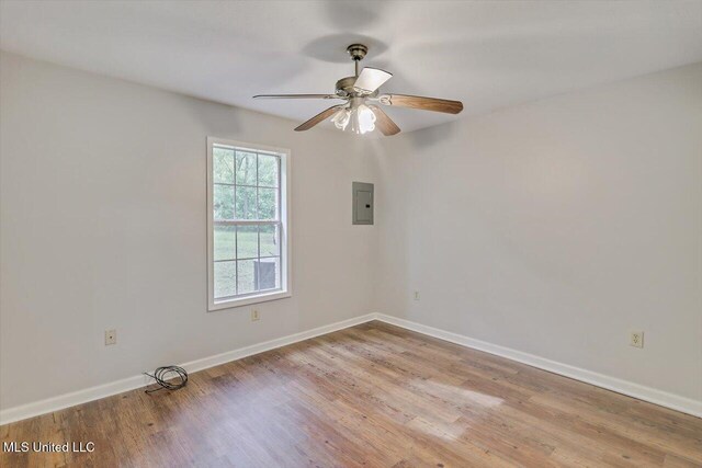 empty room with a ceiling fan, baseboards, wood finished floors, and electric panel
