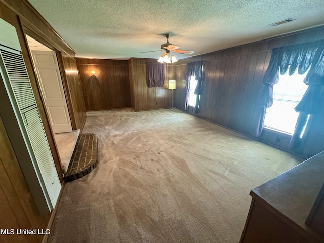 221 S Oak Ave, Ruleville, MS 38771 - unfurnished bedroom with light colored carpet, a textured ceiling, multiple windows, wood walls, and a heating unit