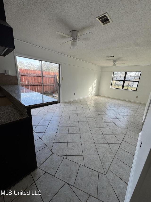 unfurnished living room with a wealth of natural light, light tile patterned floors, and ceiling fan