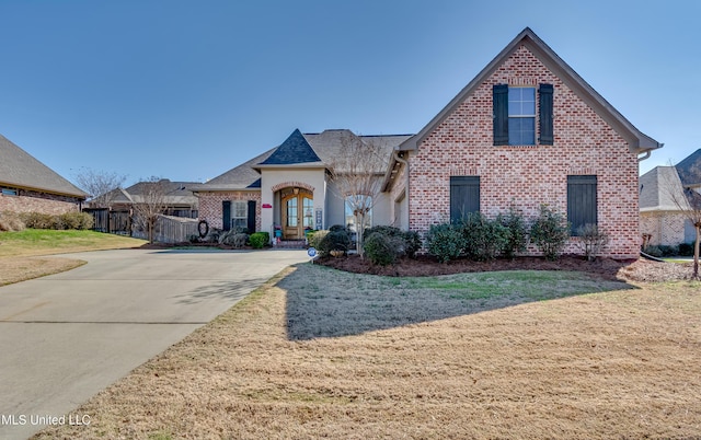 view of front of home featuring brick siding, driveway, french doors, and a front yard