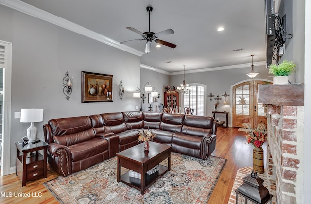 living room featuring visible vents, light wood-style flooring, crown molding, and ceiling fan with notable chandelier