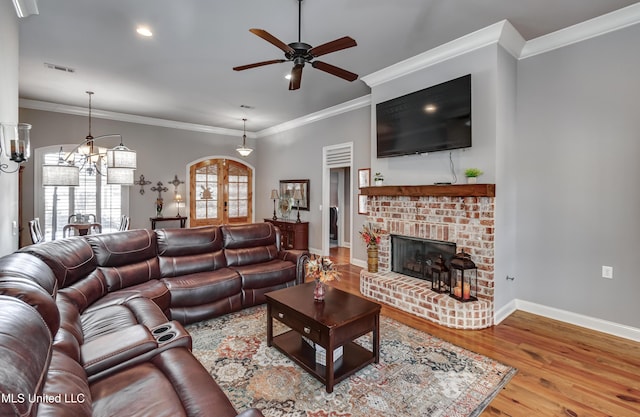 living room with wood finished floors, visible vents, baseboards, a fireplace, and ceiling fan with notable chandelier