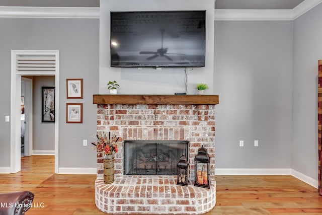 living room featuring a fireplace, crown molding, wood finished floors, and baseboards