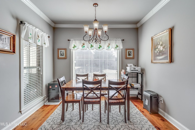 dining room with crown molding, light wood-style flooring, a notable chandelier, and baseboards