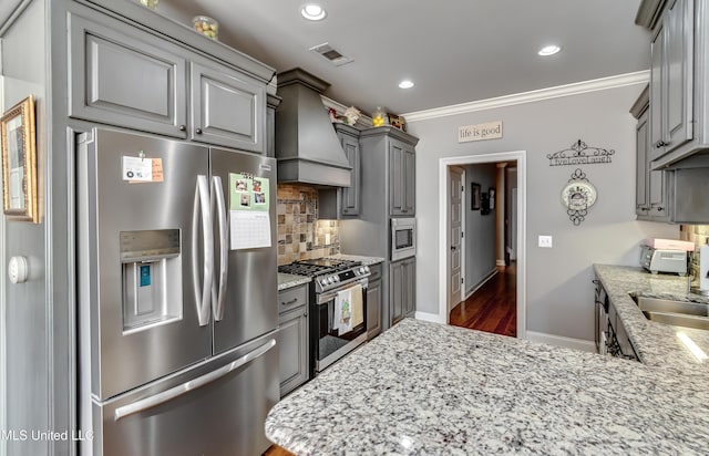 kitchen featuring premium range hood, visible vents, gray cabinetry, tasteful backsplash, and stainless steel appliances