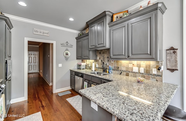 kitchen with a peninsula, gray cabinetry, stainless steel appliances, a sink, and crown molding