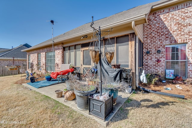 back of house featuring brick siding, a patio area, a yard, and roof with shingles