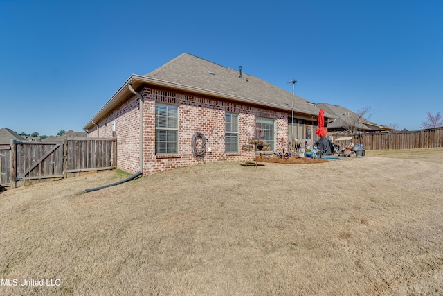 back of property with a patio, brick siding, a fenced backyard, and a gate