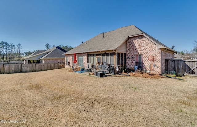 rear view of house with a yard, brick siding, fence private yard, and a patio area