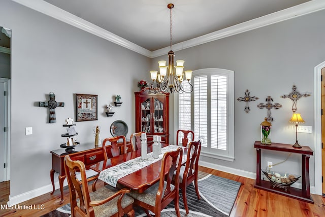 dining area featuring baseboards, a notable chandelier, wood finished floors, and crown molding