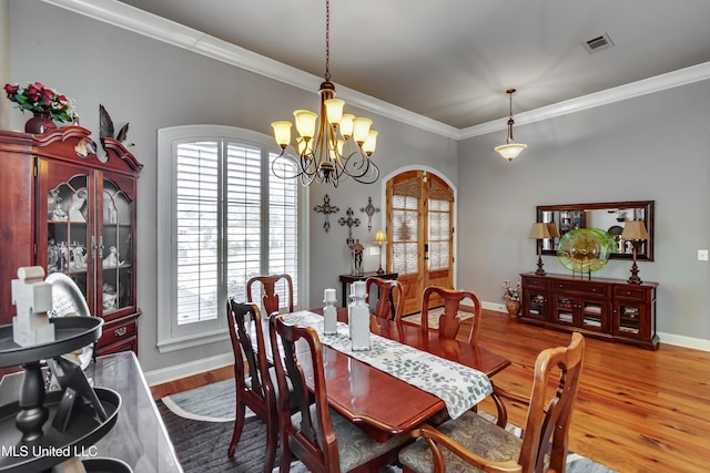 dining room with visible vents, crown molding, an inviting chandelier, wood finished floors, and arched walkways