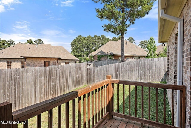 wooden terrace with a lawn and a fenced backyard